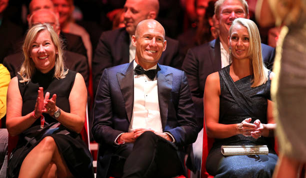 罗本与奖杯的合影特写，他嘴角上扬的弧度恰到好处，西装领带一丝不苟，身后的颁奖背板映出他职业生涯的高光时刻