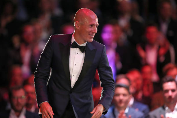 罗本身着笔挺西装，在聚光灯下微笑着举起“主编特别奖”奖杯，眼神中闪烁着对职业生涯的骄傲与感激