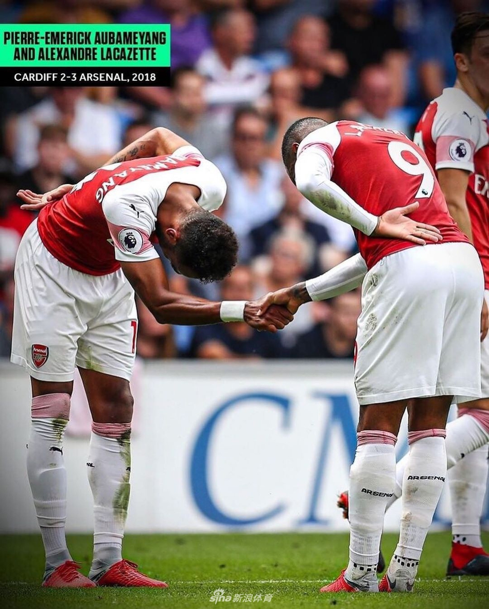 拉卡泽特与奥巴梅扬面对面站立，互相庄重敬礼，如同骑士间的致意，象征着坚不可摧的锋线兄弟情。