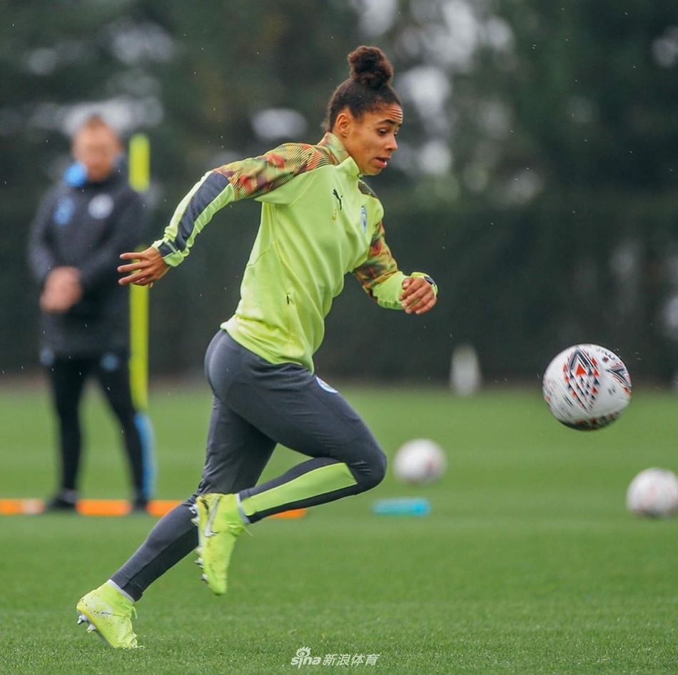 两名曼城女足球员在训练间隙并肩而行，她们凑在一起说笑，神情专注而开心，仿佛在分享一个只有她们知道的小秘密。