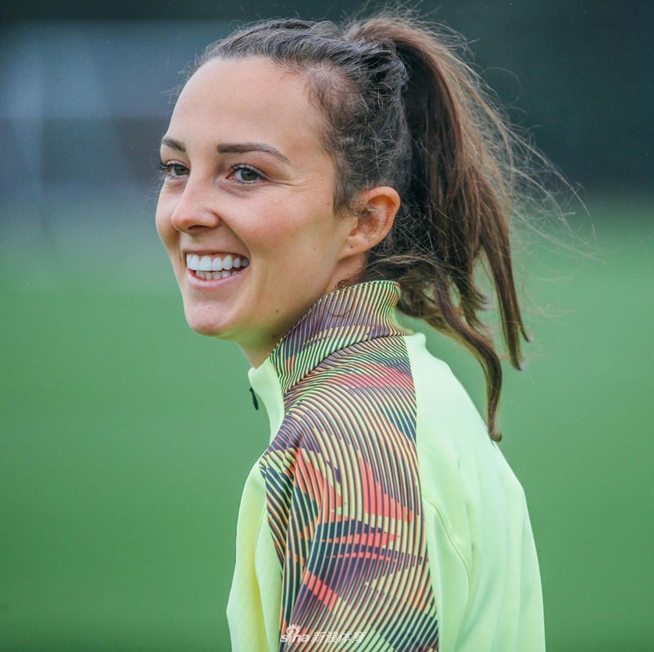 训练场上，一位曼城女足球员正带着球灵巧地转身，脸上洋溢着轻松愉快的笑容，身后的队友们也在阳光下拉开了训练的阵型。