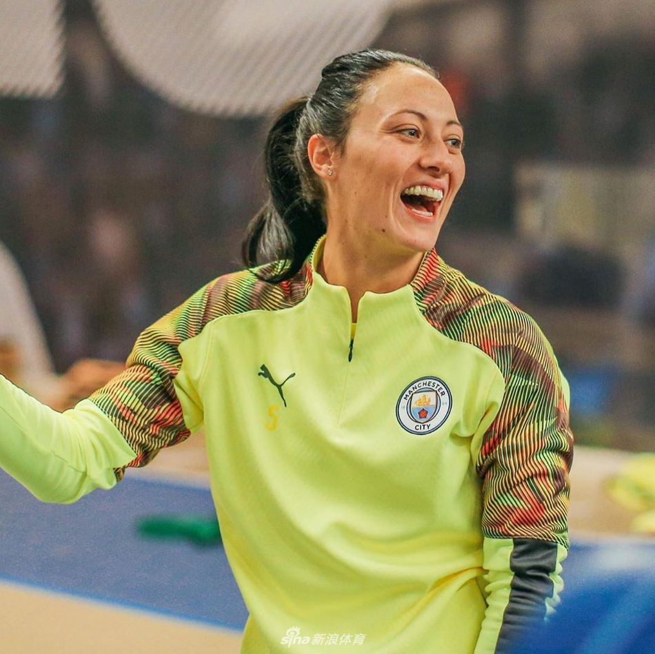 一名曼城女足球员完成训练后放松地坐在地上，正仰头开怀大笑，明媚的阳光勾勒出她充满活力的轮廓，快乐的情绪极具感染力。