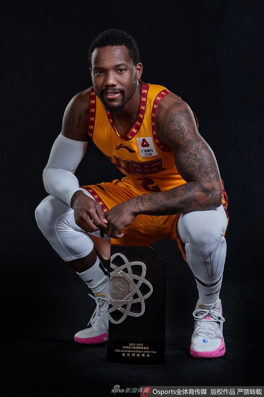 费尔德双手紧紧握住篮球置于胸前，手臂肌肉暴起的青筋显示着他的力量，球衣上的山西队徽在闪光灯下熠熠生辉。