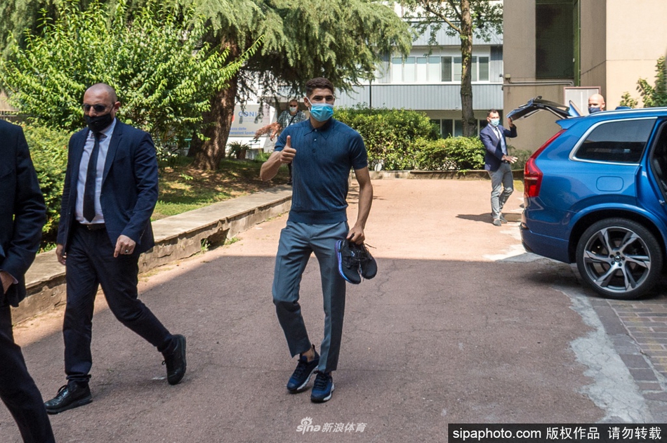 在机场到达大厅的一角，阿什拉夫耐心地为等候多时的球迷签名，嘴角带着一丝温和的微笑。他身着简单的白色T恤，专注的神情显示出他对支持者的尊重，周围的人群和闪光灯记录下了这亲切互动的一刻。