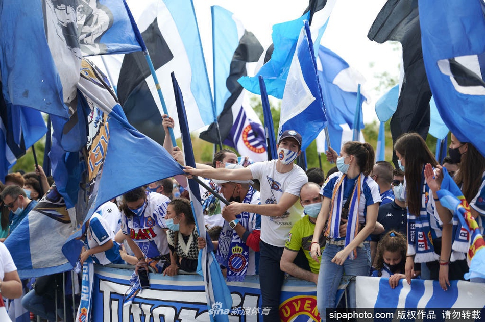 在RCDE球场外，一位满脸涂着蓝白油彩的小球迷骑在父亲肩头，双手指向天空，庆祝球队升级。