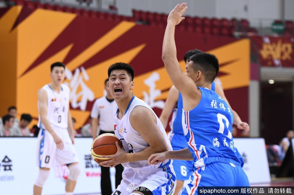 河南队核心后卫在对方严密防守下强行突破,身形如弓,篮球即将离手划出优美弧线。