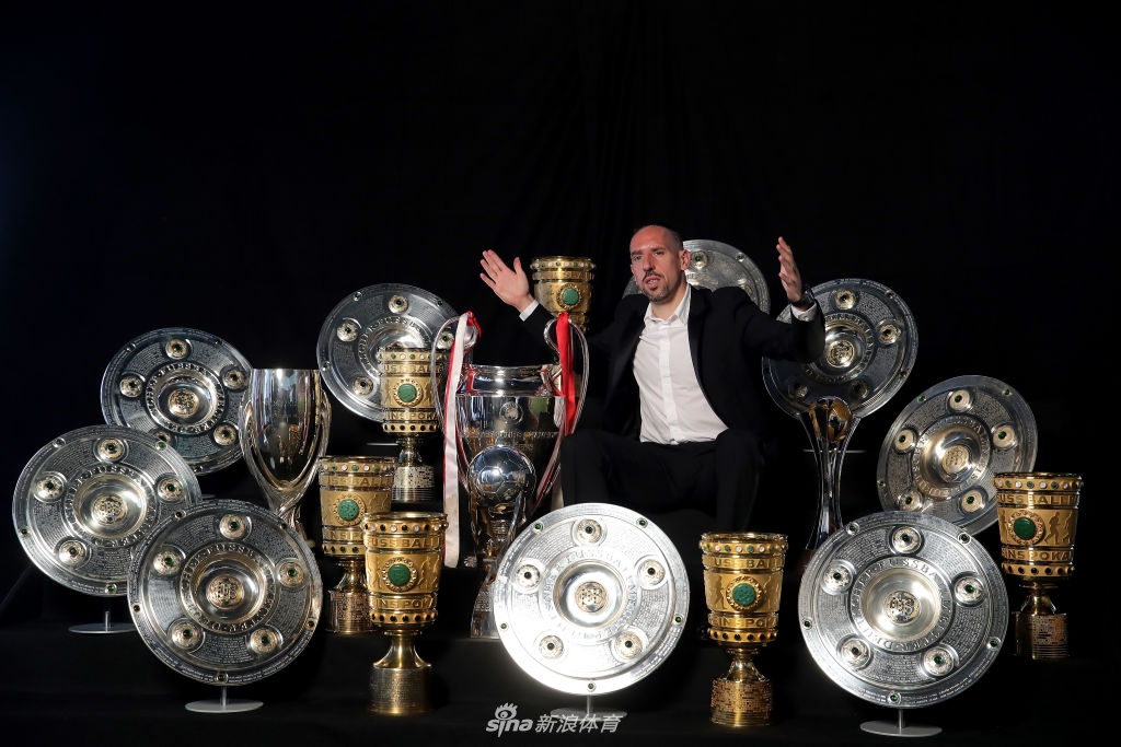 罗本和里贝里低头仔细端详着一块德甲冠军金牌，金牌在灯光下闪耀，两人神情专注，仿佛在回忆为这块奖牌付出的所有努力。