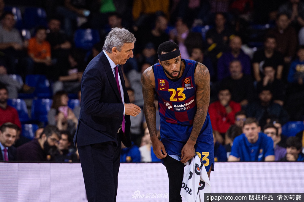 巴塞罗那篮球队员在训练馆中围成一圈，拳头紧握相互鼓劲，展现出在疫情阴霾下团结一心的坚定力量。