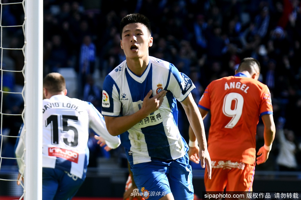 训练场上，一名球员正独自进行带球绕杆练习，他的眼神专注而坚定，身后是空旷的看台和一片静谧的春日天空。