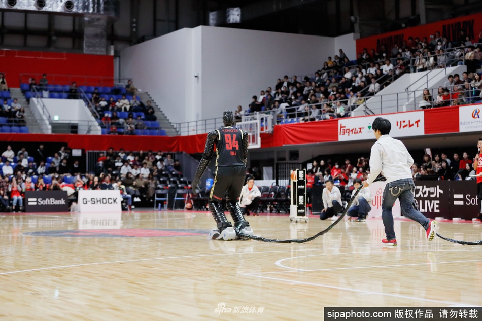 Cue系列机器人正以标准投篮姿势出手，篮球在空中划出优美弧线，其机械手臂关节的精密构造和专注的‘独眼’视觉系统清晰可见，仿佛一位冷靜的得分后卫在赛场中央完成致命一击。