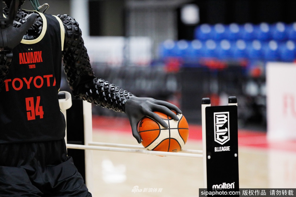 技术人员正在对Cue机器人进行调试，他的手指轻触着机器人的机械结构。这台身高超过两米的机器人静静地站立着，其充满金属质感的躯体与技术人员专注的神情，共同构成了一幅人机协作、共同追求极致精准的科技画面。