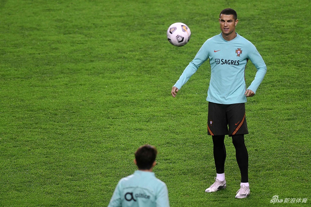 C罗正在进行标志性的电梯球练习，皮球划出一道美妙的弧线直挂球门死角，连场边的摄影记者都忍不住为之赞叹。