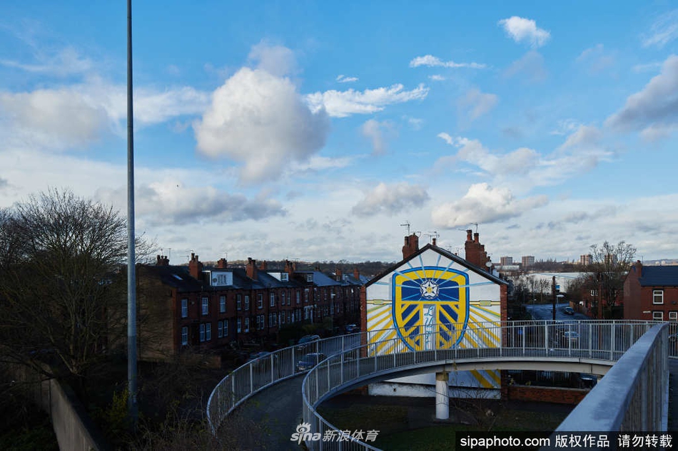 在利兹市中心的高墙上，巨幅壁画震撼亮相，艺术家正精心勾勒着利兹联传奇人物的轮廓，让历史与现代在这座城市的上空交汇。