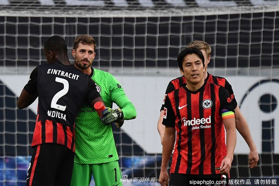 在法兰克福的主场德意志银行公园，长谷部诚佩戴队长袖标，正在鼓掌感谢看台上支持他的球迷，阳光洒在他身上，映照出一人一城的忠诚画面。