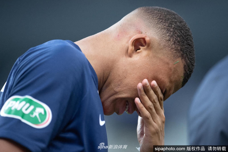 雨中激战的姆巴佩，球衣紧贴身躯，湿透的头发甩出的水珠与赛场上的雨丝交织，眼神中透露出与年龄不符的坚毅与冷峻，仿佛在雨战中独自思考着未来的方向。