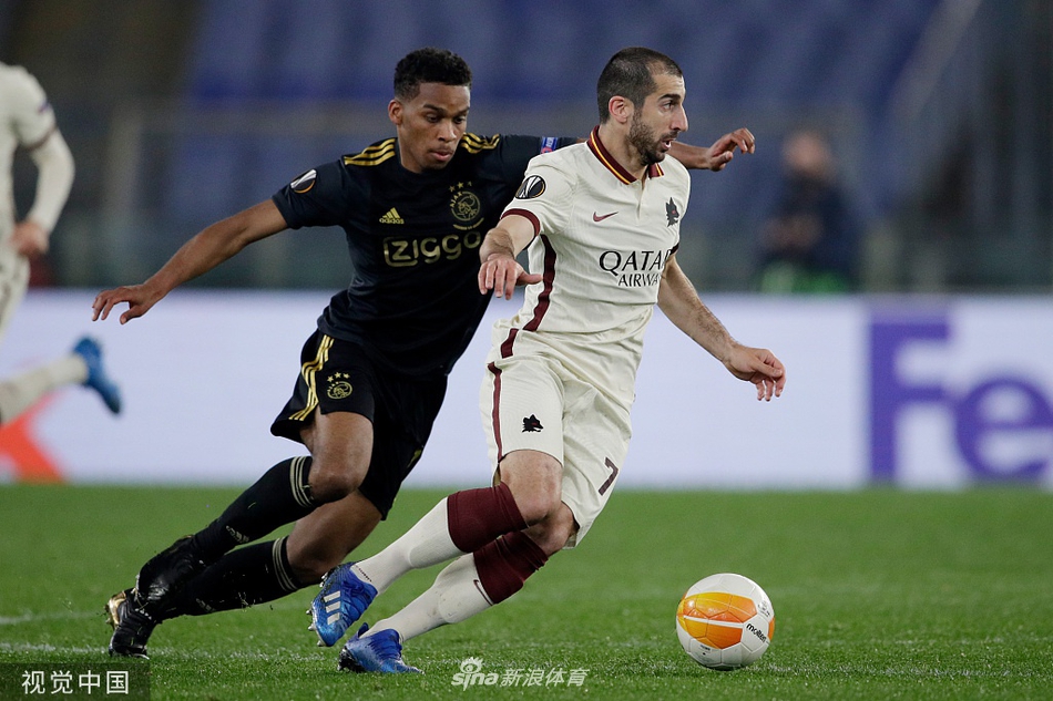 罗马与阿贾克斯球员在奥林匹克体育场激烈拼抢，红狼战袍与白衣军团在夜色下形成鲜明对比，空气中弥漫着大战的紧张气息