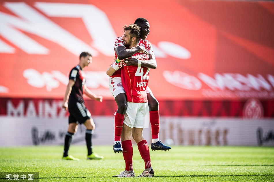 美因茨球员在打入第二粒进球后，与队友在角旗区附近忘情庆祝，看台上的球迷们挥舞着围巾，汇成一片欢乐的红色海洋