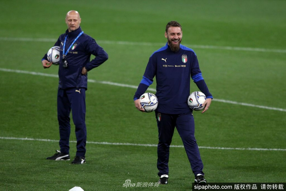 德罗西俯身倾听小球员的困惑，岁月磨平了他赛场上的桀骜，却平添了几分师者的从容，他正将自己的足球智慧像浇灌树苗般滋养着下一代。