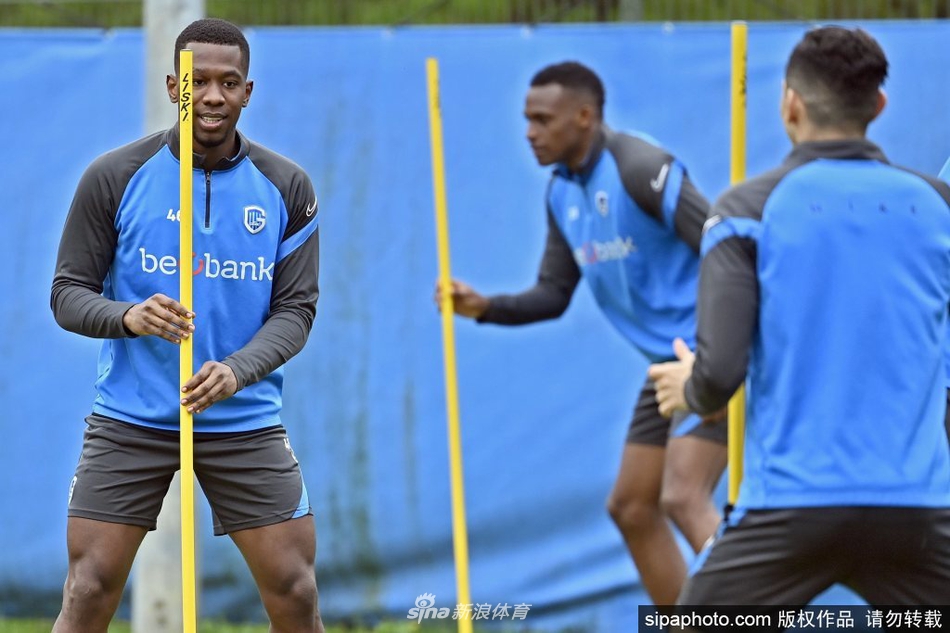 门将全神贯注，飞身扑救来球，身后是排列整齐的训练器材和队友们关注的目光。