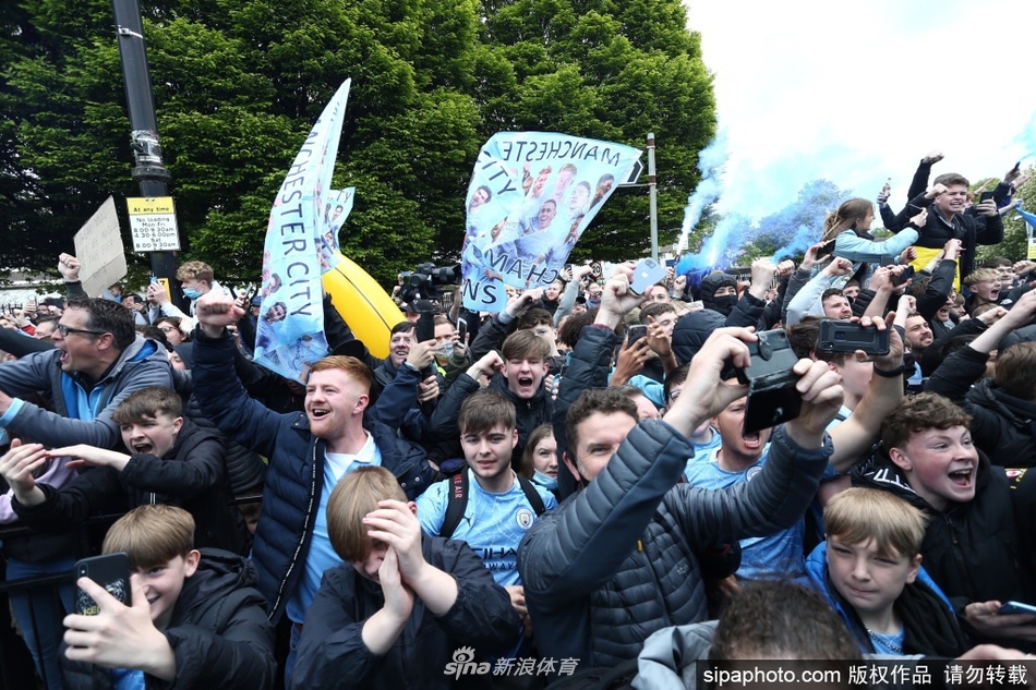 数不清的曼城球迷将伊蒂哈德球场外的街道围得水泄不通，他们高举着天蓝色的围巾和旗帜，在烟雾弹的映衬下，将现场变成了一片欢乐的蓝色海洋。