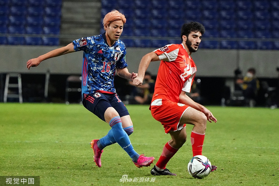 南野拓实门前飞身铲射破门后，从草地上起身，与为自己助攻的古桥亨梧击掌相庆，两人脸上洋溢着默契的笑容，背景是略带失落的塔吉克斯坦防守队员。