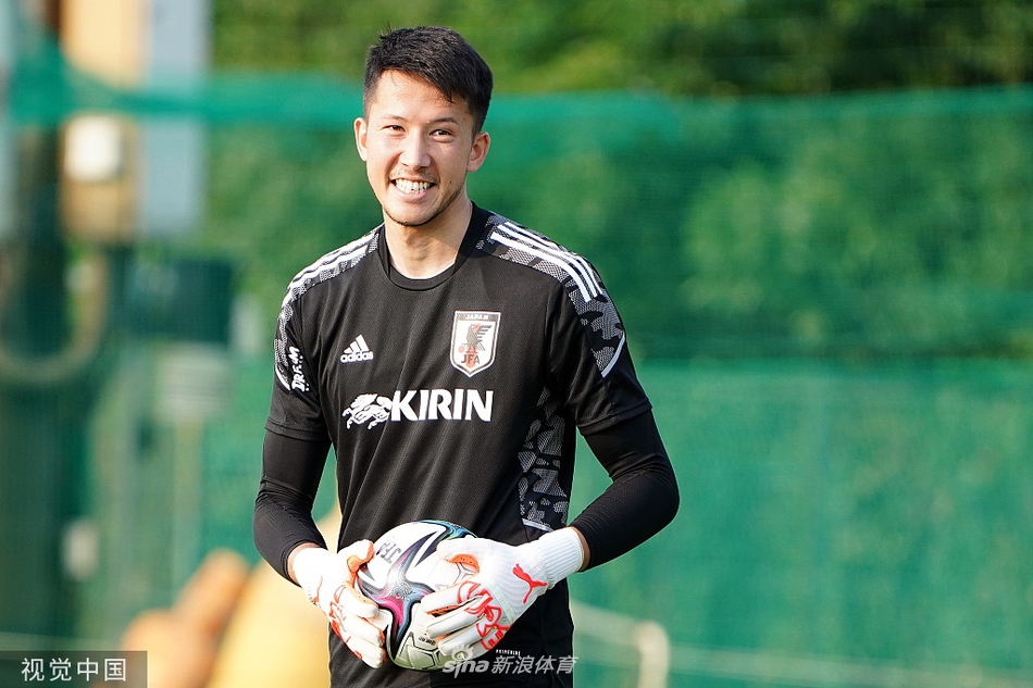 守门员教练正在对一名日本队门将进行一对一的指导。门将全神贯注地聆听着，身体微微前倾，随时准备按照教练的指示做出下一个扑救动作，身后的球门就是他需要守护的阵地。