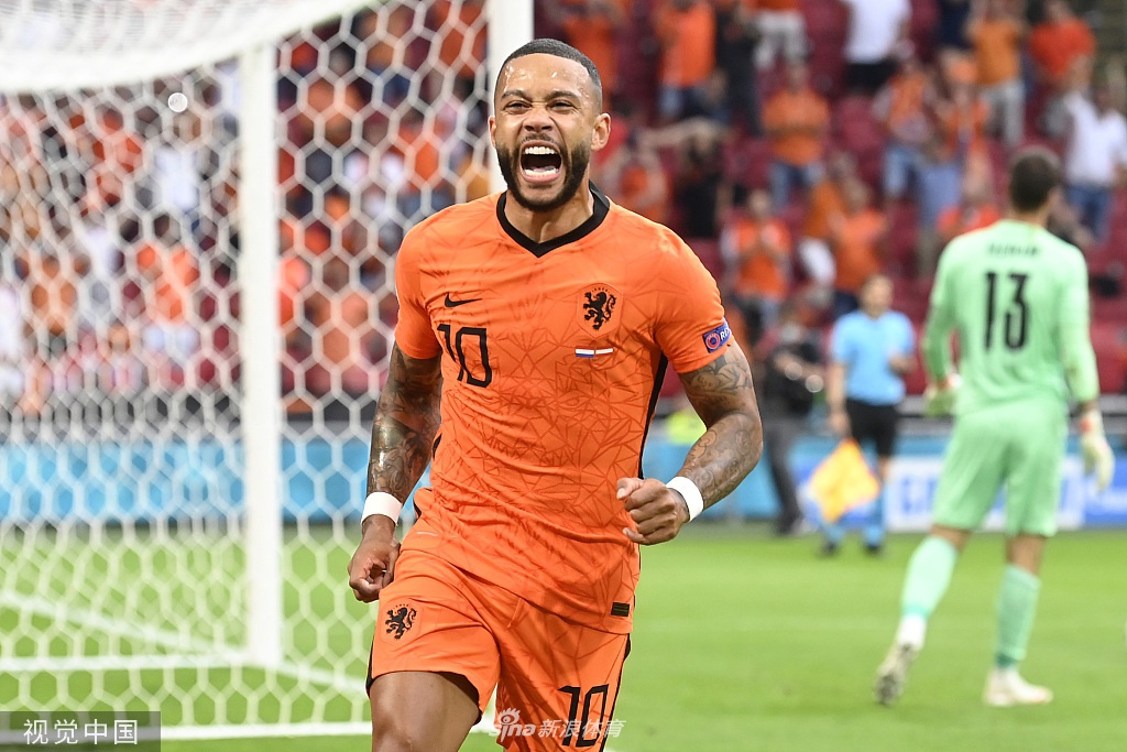 德佩在打入点球后激情庆祝，身后的队友们飞奔而来，分享这粒打破僵局的关键进球的喜悦。