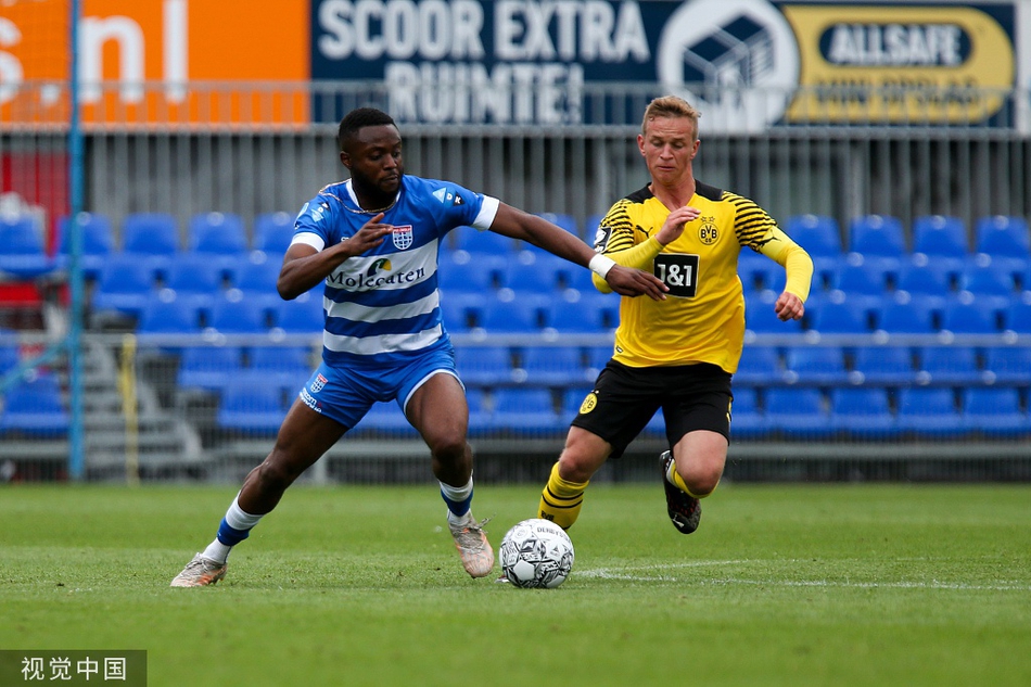 多特蒙德U23队一名中场球员在贴身逼抢下用胸部优雅地停下高空来球，他身旁的兹沃勒防守球员正侧身观察，试图寻找断球良机