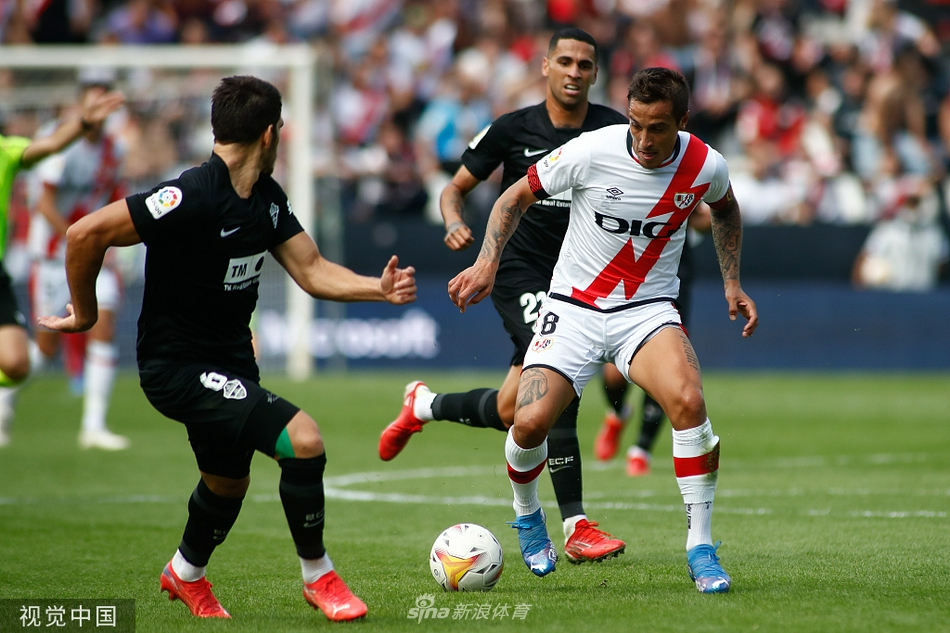 巴列卡诺主帅伊劳拉在场边激情指挥，他张开的双臂和专注的神情极具感染力，身后教练组成员也纷纷起身，紧张地关注着场上瞬息万变的局势。