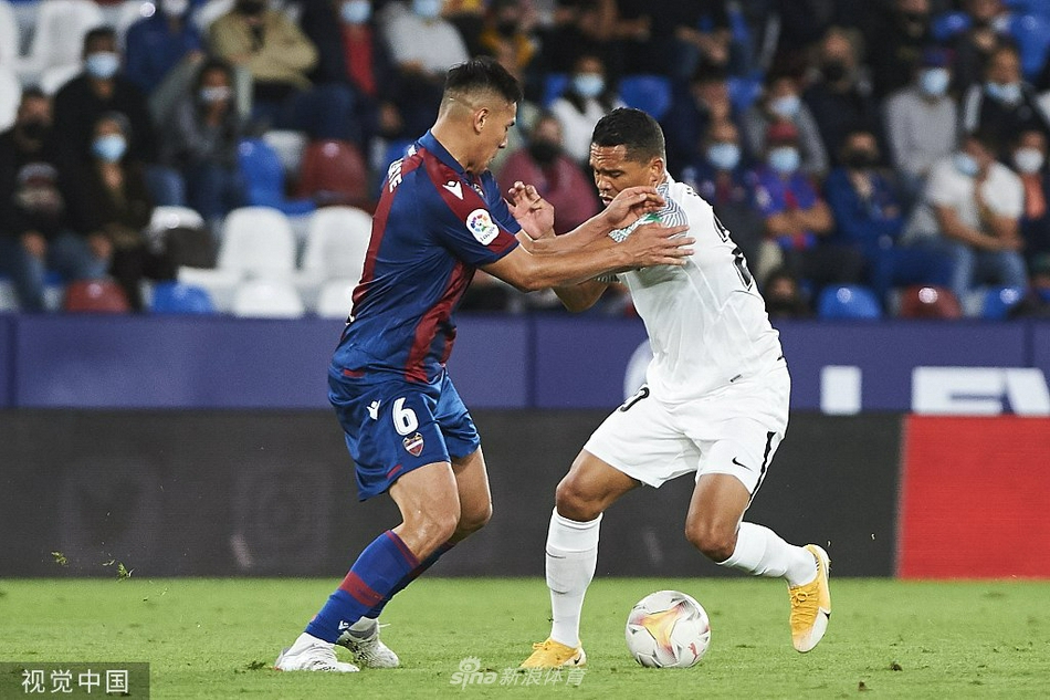 莱万特门将艾托尔-费尔南德斯在球门前无奈地弯腰低头，双手撑膝，背景是格拉纳达球员的庆祝身影，他孤独的背影映衬出球队两球落后时的绝望与失落。