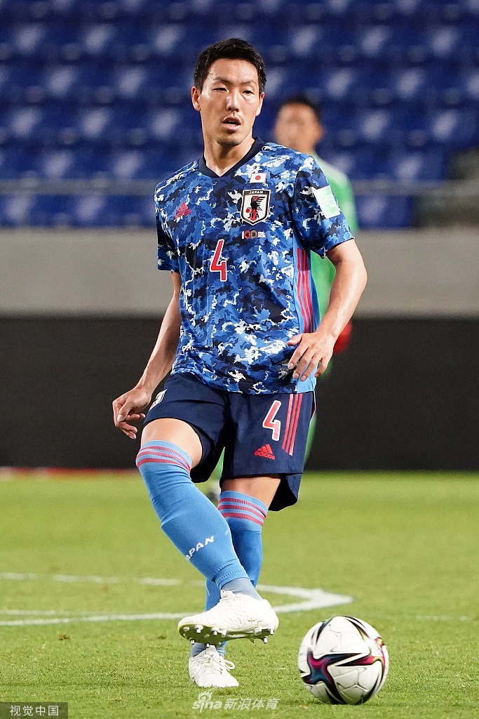 桥本拳人射门瞬间，他的身体舒展，眼神坚毅地盯着飞向球门的皮球，背景是虚化的球场和看台，仿佛整个世界都聚焦于这记精彩绝伦的远射。