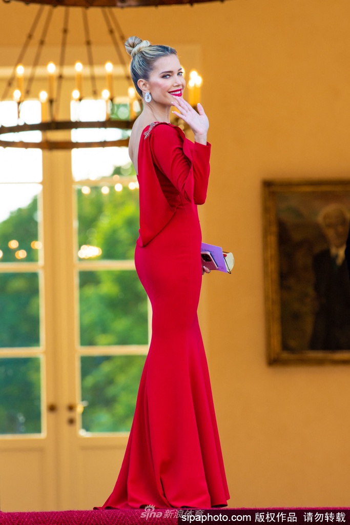 西尔维·梅斯侧身而立，红色单肩礼服紧贴身形勾勒出完美曲线，高开叉设计若隐若现露出修长美腿，性感得恰到好处。