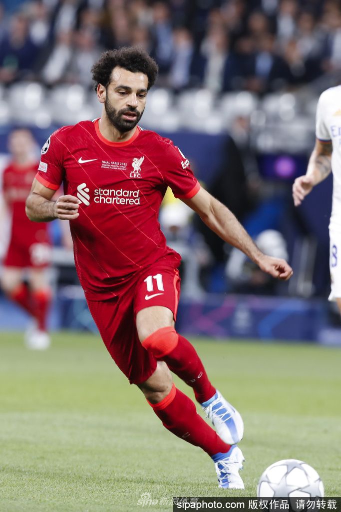 萨拉赫在安菲尔德球场奔跑庆祝进球，阳光照亮他自信的笑容