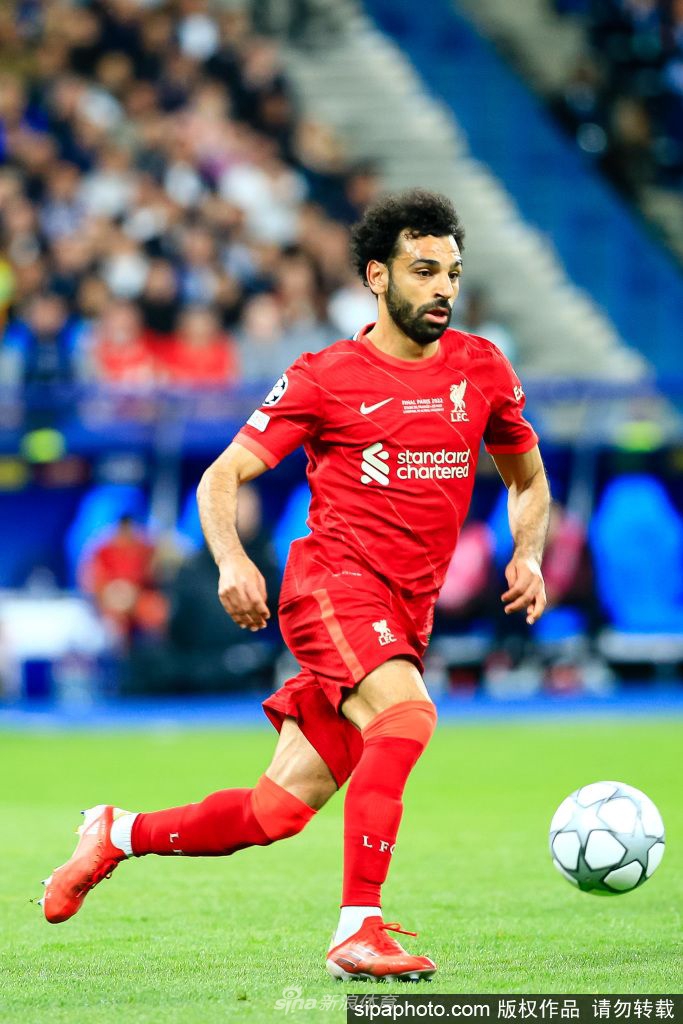 埃及球星萨拉赫身着国家队战袍，在赛场边凝神思考，肩负国家荣耀。