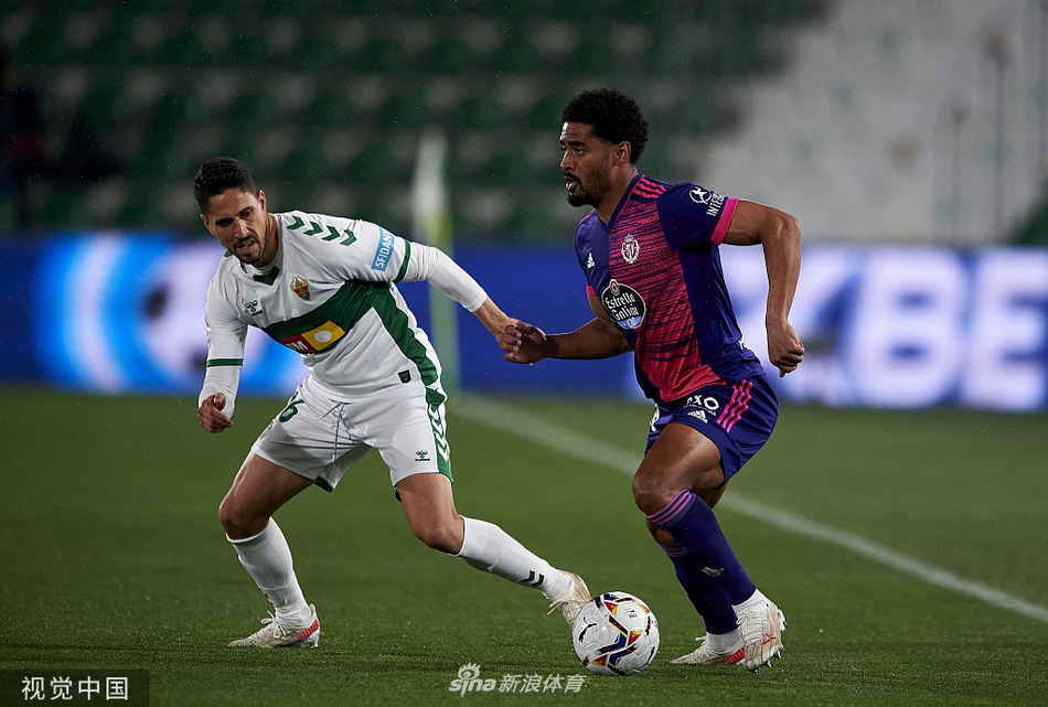 终场哨响，埃尔切球员卢卡斯-博耶难掩失望之情，双手叉腰低垂着头，眼神空洞地望着球场，与身旁激动庆祝的巴拉多利德球员形成鲜明对比。