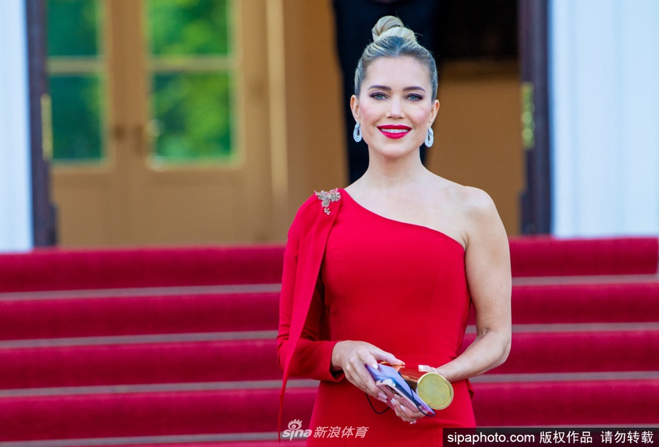 西尔维·梅斯回眸瞬间，红色单肩礼服裙摆随步伐摇曳，在柏林夏夜的微风中绽放出如同烈焰般的生命力。