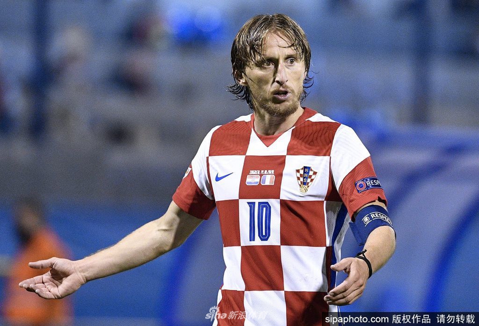 终场哨响后，莫德里奇并未立即离场，他脱下球衣，露出健硕的身躯，正与裁判交换纪念品。夕阳的余晖洒在他汗津津的背上，映照出的是一位即将加冕队史出场王者的荣耀与坦然。