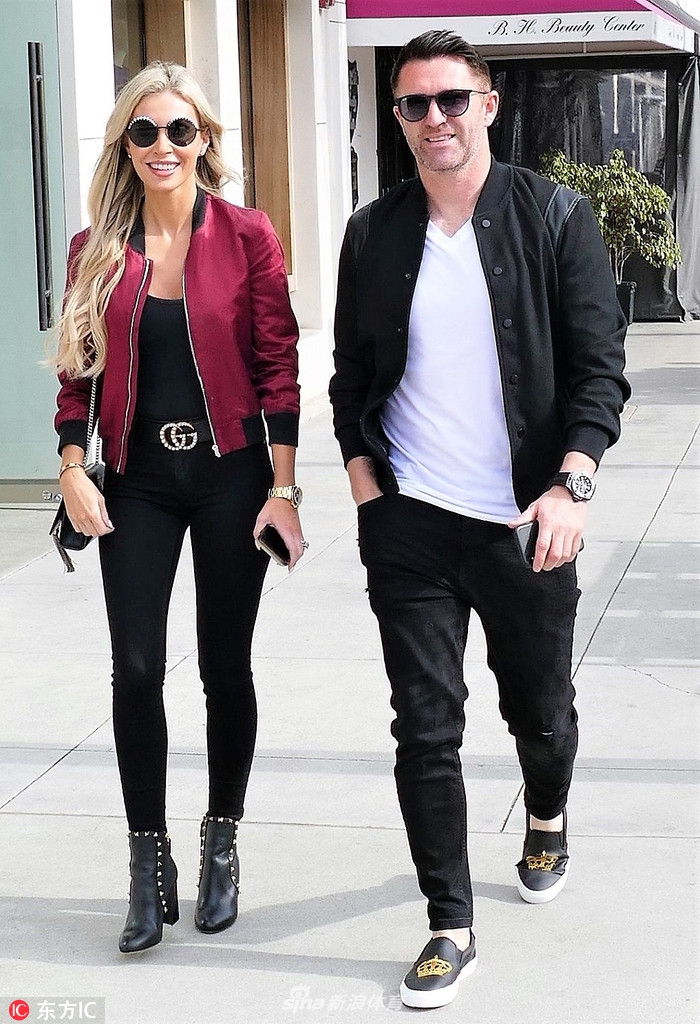 罗比·基恩与娇妻克劳丁在比弗利山庄街头漫步，阳光洒在两人身上，他一身休闲装扮显得帅气有型，而她则笑容灿烂，夫妻俩面对镜头显得心情极佳。