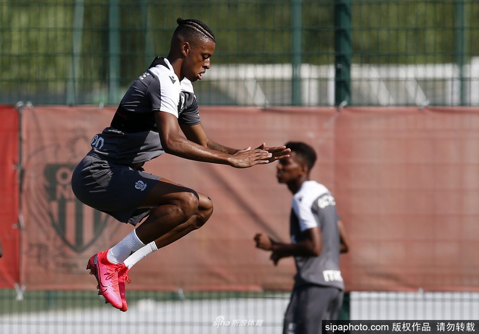 训练间歇，一名尼斯球员俯身整理鞋带，汗珠顺着脸颊滴落在草地上，折射出阳光的晶莹。