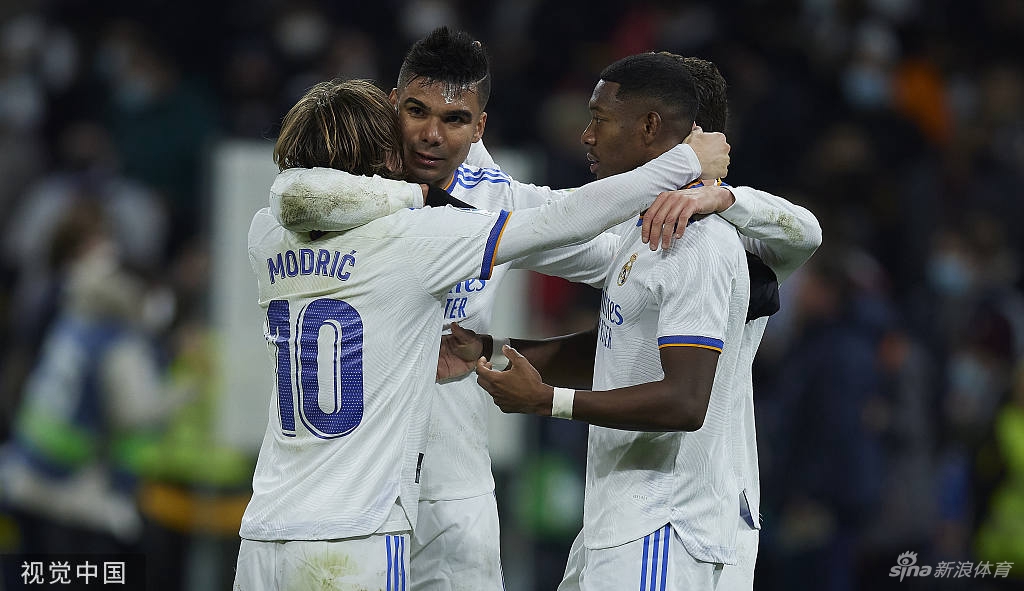 皇马主帅安切洛蒂在场边沉着指挥，手抚下巴若有所思，尽显战术大师风范，身后是紧张注视赛场局势的替补席成员。