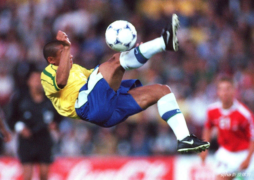 夺冠后的卡洛斯忘情庆祝，双手指天，脸上洋溢着孩子般纯真的笑容，身边是簇拥的队友和飘扬的旗帜