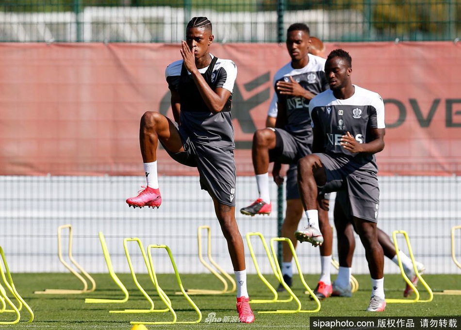 尼斯球员在慢跑中侧耳倾听教练的战术部署，远处的训练设施在晨光中勾勒出线条，整个画面仿佛一幅关于准备的油画。