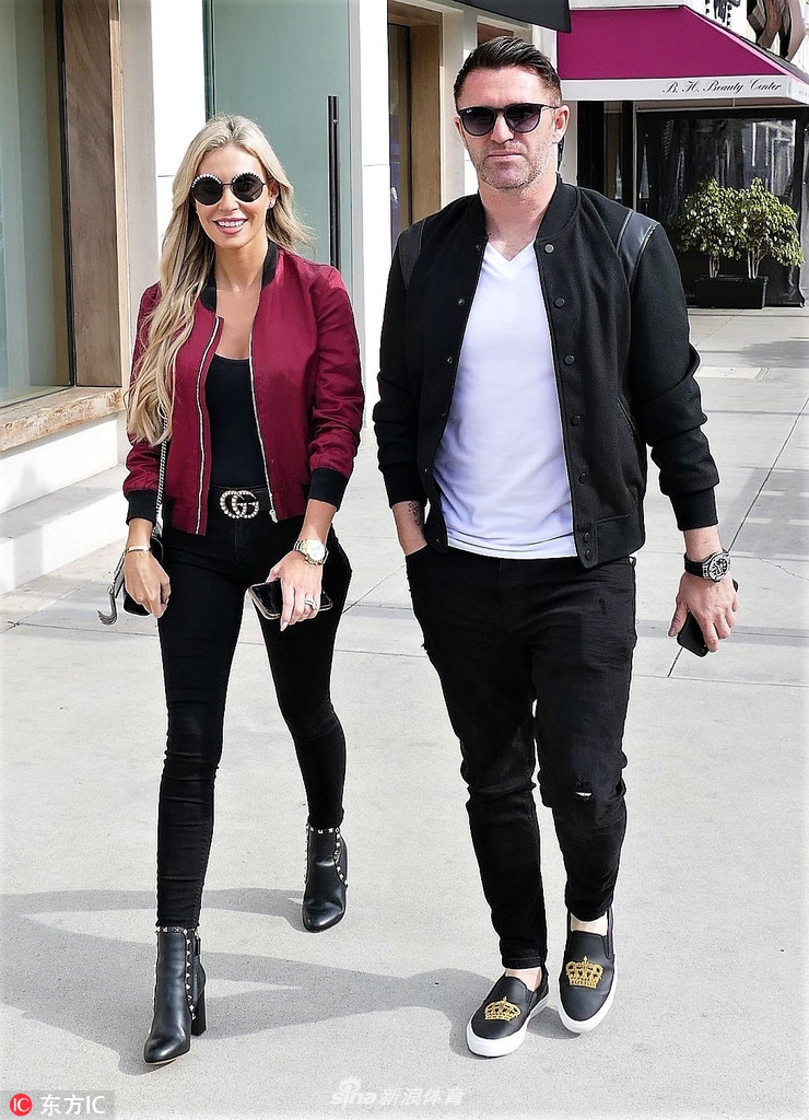 罗比·基恩与妻子克劳丁在美国比弗利山庄街头驻足，两人相视而笑，眼神中满是爱意，克劳丁的休闲装扮与基恩的随性搭配相得益彰，完美展现了这对明星夫妇的日常幸福瞬间。