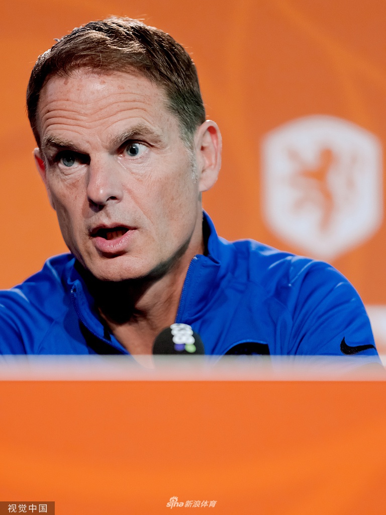 一名记者正在用手机拍摄发布会细节，背景是荷兰国家队的巨大队徽，氛围感十足