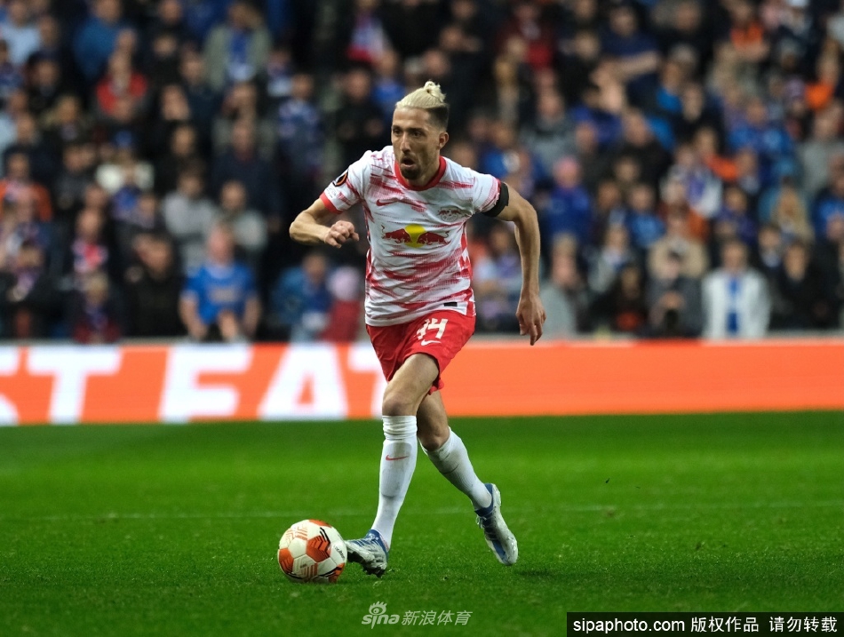 坎普尔手持莱比锡红牛球衣，在新合同上郑重签下自己的名字，脸上洋溢着续约后的喜悦与坚定。