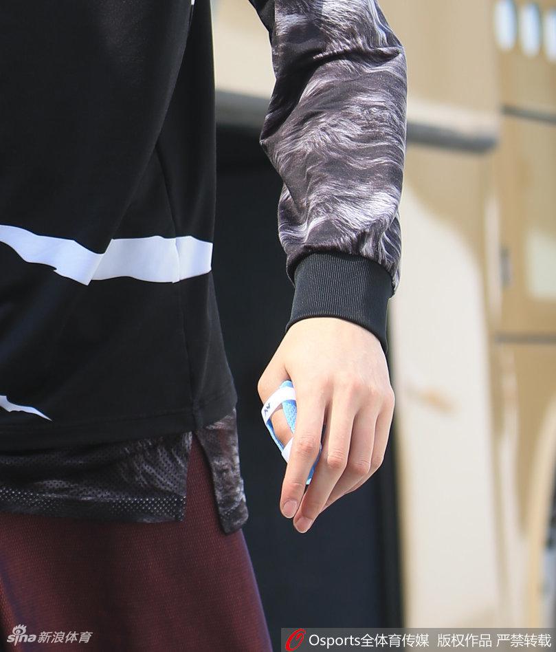 李根手提篮球鞋,大步流星地走在通往训练馆的通道上,眼神坚定,展现出总决赛关键先生的气场与自信。