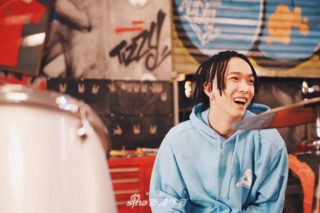 欧阳靖在充满街头感的场景中做出经典手势，背景的涂鸦色彩张扬，他脚上的Yeezy 350 Boost 'Moonrock'与整个嘻哈氛围融为一体，显得既复古又前卫