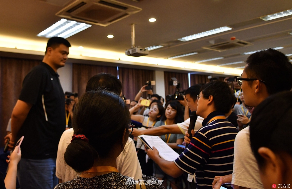 篮球巨人姚明俯身微笑，与身着红色球衣的山区小球员手掌相击，眼神里满是鼓励与温柔，定格了梦想传递的动人瞬间。