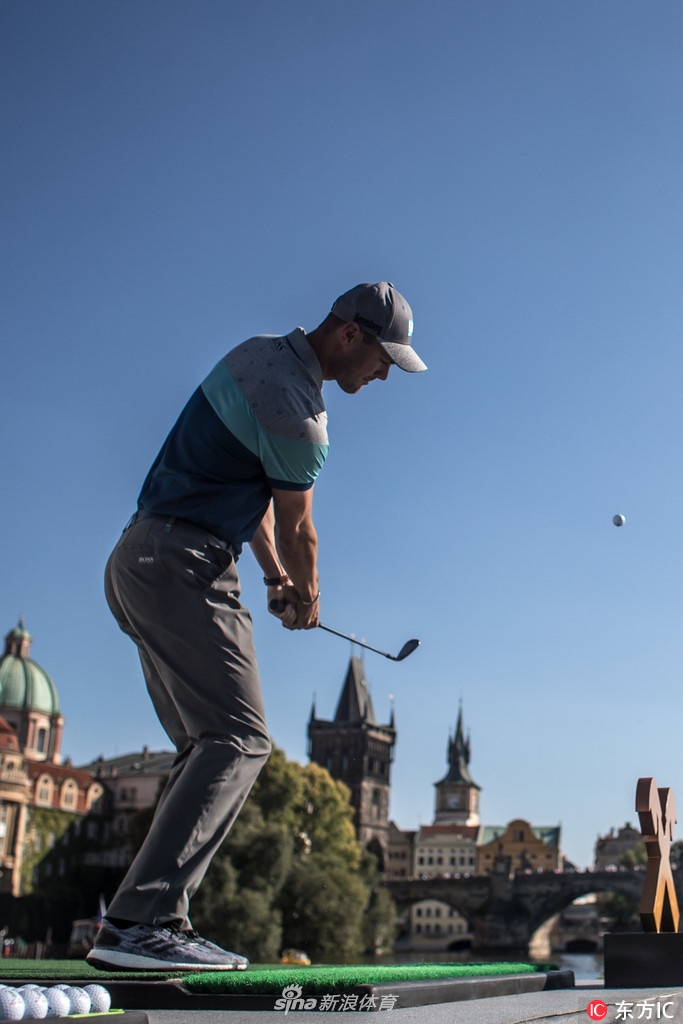 凯梅尔在河畔与小球童亲切互动,展现其亲和一面,背景中其他球星与工作人员也在为活动忙碌准备。