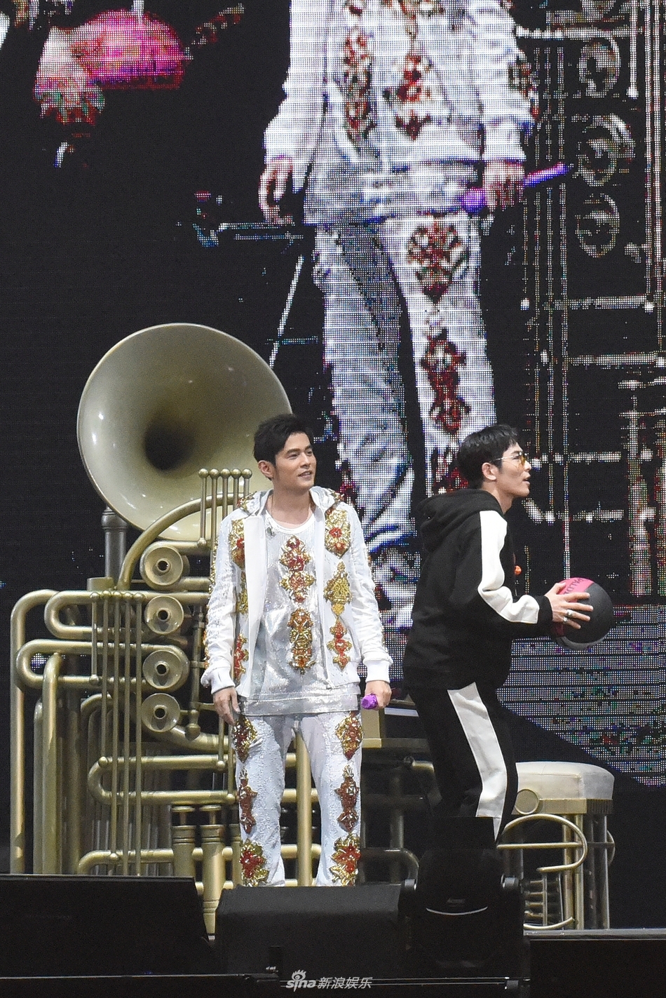 周杰伦与萧敬腾在台北小巨蛋的舞台上背对背坐着，周董坐在大喇叭造型钢琴前弹奏，两人深情合唱，画面充满音乐才子间的惺惺相惜。